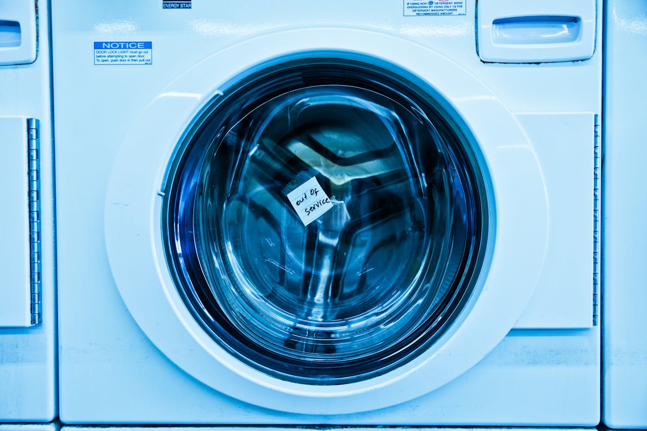 Close-up of an out-of-service washing machine in a laundromat with a blue tint.